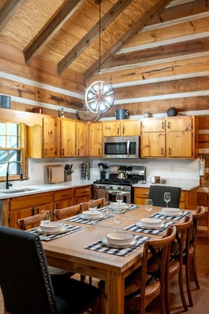 A rustic wooden kitchen with a dining table set for four, equipped with modern appliances and ample storage. - Enchanting Creekside Mountain Cabin Retreat with Luxury Amenities in the Heart of Scenic Blue Ridge, Georgia (Blue Ridge)