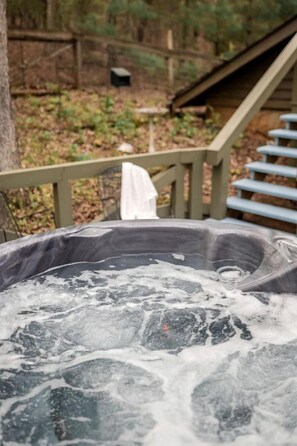 A hot tub with a wooden deck and stairs leading to a covered area. - Enchanting Creekside Mountain Cabin Retreat with Luxury Amenities in the Heart of Scenic Blue Ridge, Georgia (Blue Ridge)
