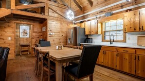 Ein Holzinterieur mit einem Esstisch, Stühlen und einer Küchenzeile mit Holzschränken und Geräten.