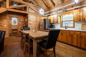 Ein Holzinterieur mit einem Esstisch, Stühlen und einer Küchenzeile mit Holzschränken und Geräten.