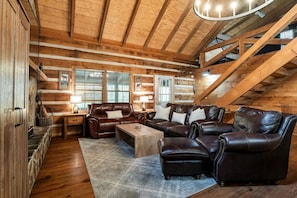 A log cabin interior with a wooden ceiling, leather furniture, and a staircase. - Enchanting Creekside Mountain Cabin Retreat with Luxury Amenities in the Heart of Scenic Blue Ridge, Georgia (Blue Ridge)