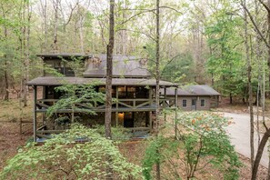 A two-story cabin with a balcony, surrounded by forest. - Enchanting Creekside Mountain Cabin Retreat with Luxury Amenities in the Heart of Scenic Blue Ridge, Georgia (Blue Ridge)