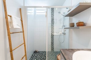 Et moderne badeværelse med en glasbrusekabine, en træstige og et flisegulv.
