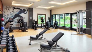 Ein Fitnessraum mit Kraftgeräten, Kurzhanteln und einer Trainingsbank.