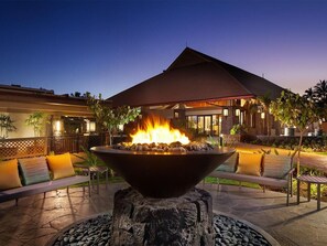 An outdoor seating area with a fire feature in the center, surrounded by lounge chairs and a stone fire pit base. - Family-Friendly 2 Bedroom Villa at Kaua'i Resort (Koloa)