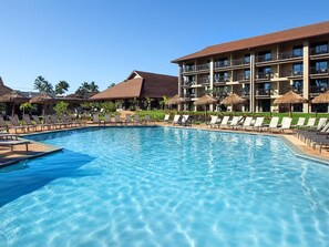 A swimming pool with lounge chairs and a hotel building in the background. - Family-Friendly 2 Bedroom Villa at Kaua'i Resort (Koloa)