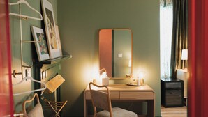 Una habitación con escritorio, dos sillas, espejo y lámpara.