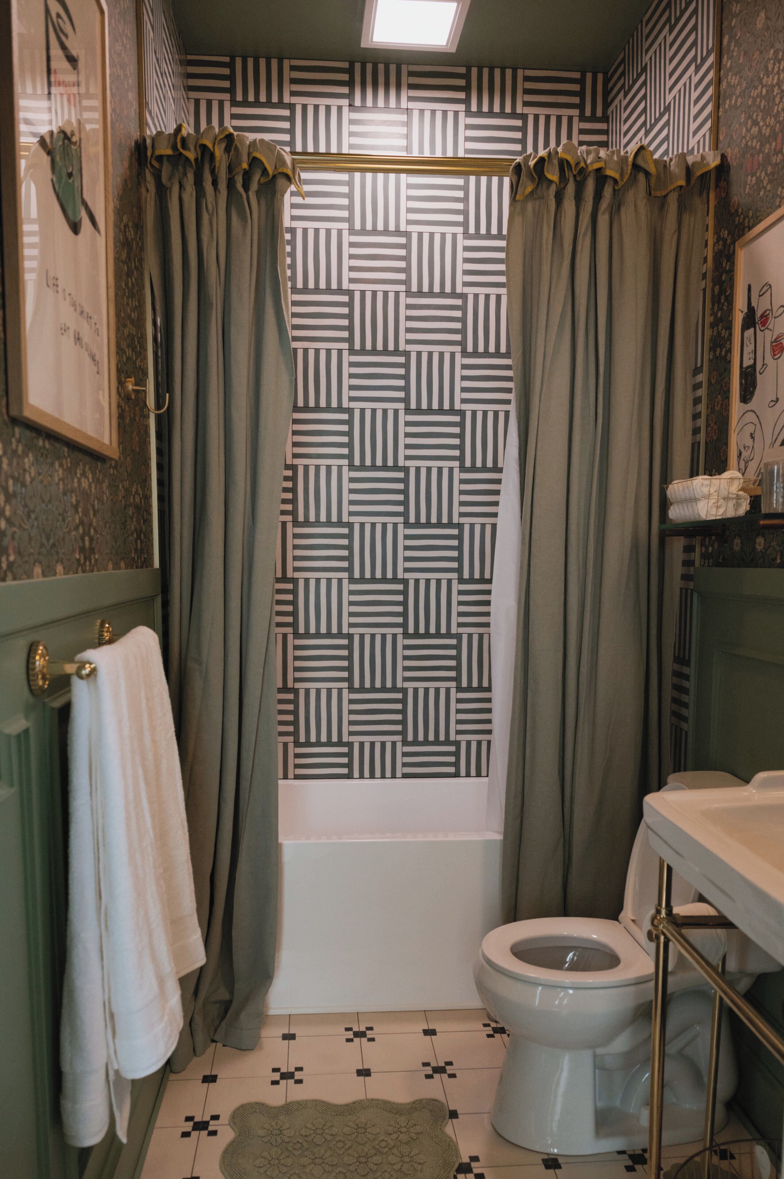 Une salle de bain avec un rideau de douche à motifs, des toilettes et un lavabo équipé d’un porte-serviettes.