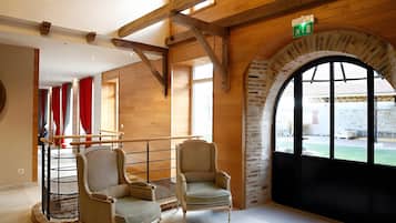 Une pièce dotée de deux fauteuils rembourrés, d’un plafond en bois et d’une grande fenêtre en arc de cercle.