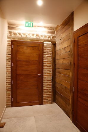 Un pasillo con una puerta de madera y una pared de ladrillo.