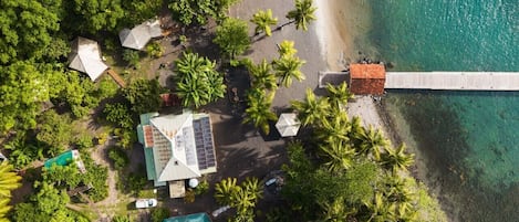 Eine Luftaufnahme eines Resorts mit Strand, Palmen und einer Anlegestelle.