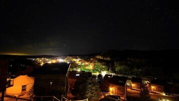 A nighttime view of a town with illuminated buildings and a starry sky.