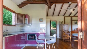 Een keuken met een inbouwoven, een eethoek met een tafel en stoelen, en een plafondventilator.