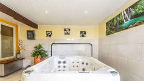 Een spa-ruimte met een jacuzzi, een potplant en een muurschildering van een waterval.