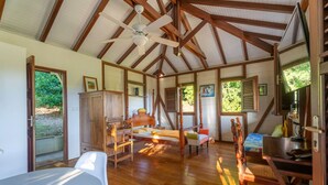 Een ruime kamer met houten plafond, een bed, een bureau en een stoel.