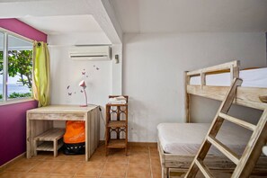 Een kamer met een stapelbed, een bureau met lamp, een stoel en een raam met gordijnen.