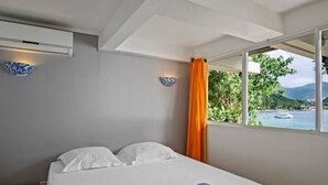 Ett hotellrum med en säng, ett fönster med utsikt över havet och en gardin.