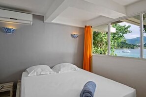 Ein Hotelzimmer mit Bett, Fenster mit Meerblick und Vorhang.