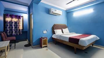 A room with a bed, a chair, an air conditioning unit, and a ceiling fan.