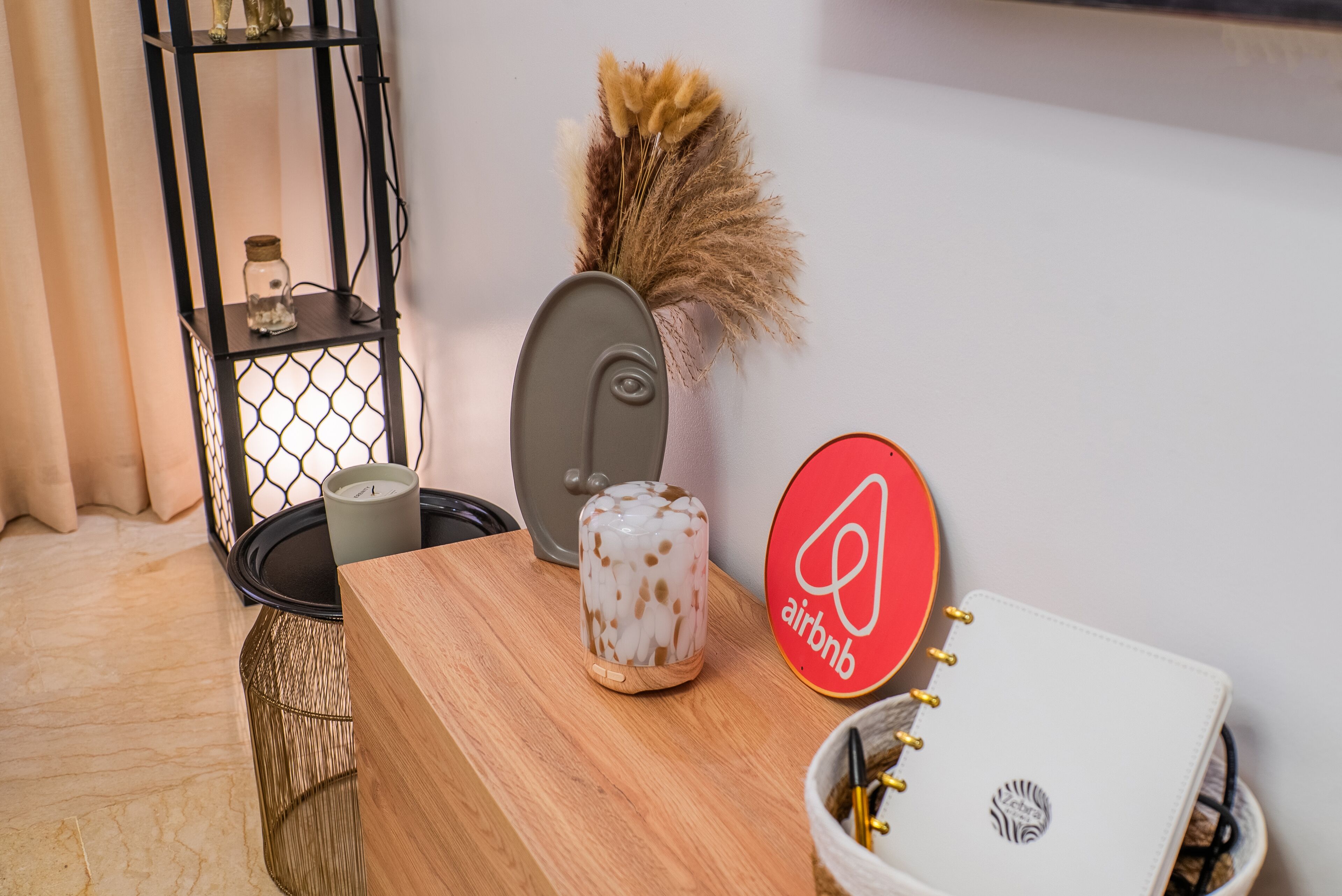 A wooden table with a candle, a decorative vase, and an Airbnb sign.