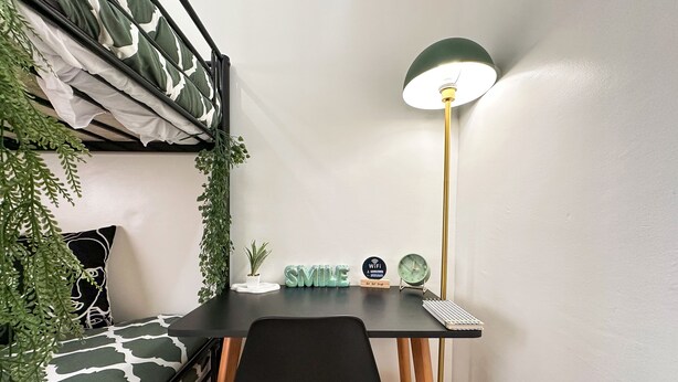 A compact room with a bunk bed, a desk with a lamp, a chair, and a small potted plant. - Stylish 2BR Apartment Near Harhoura Beach- PS5, Free Parking & Fast Wi-Fi (Temara)