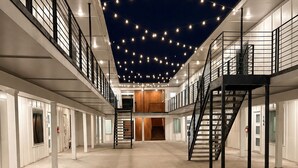 Un'ampia area interna con una scala centrale, diverse porte e un soffitto decorato con luci a stringa.