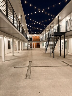 A spacious indoor area with a central staircase, multiple doors, and a ceiling adorned with string lights. - Cozy 1BR - Sleeps 4 - Walk to Downtown & Free Parking (Dallas)