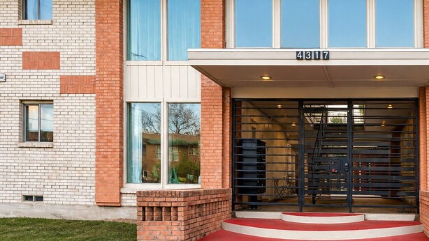 Un edificio con facciata in mattoni, ampie finestre e ingresso con tappeto rosso.