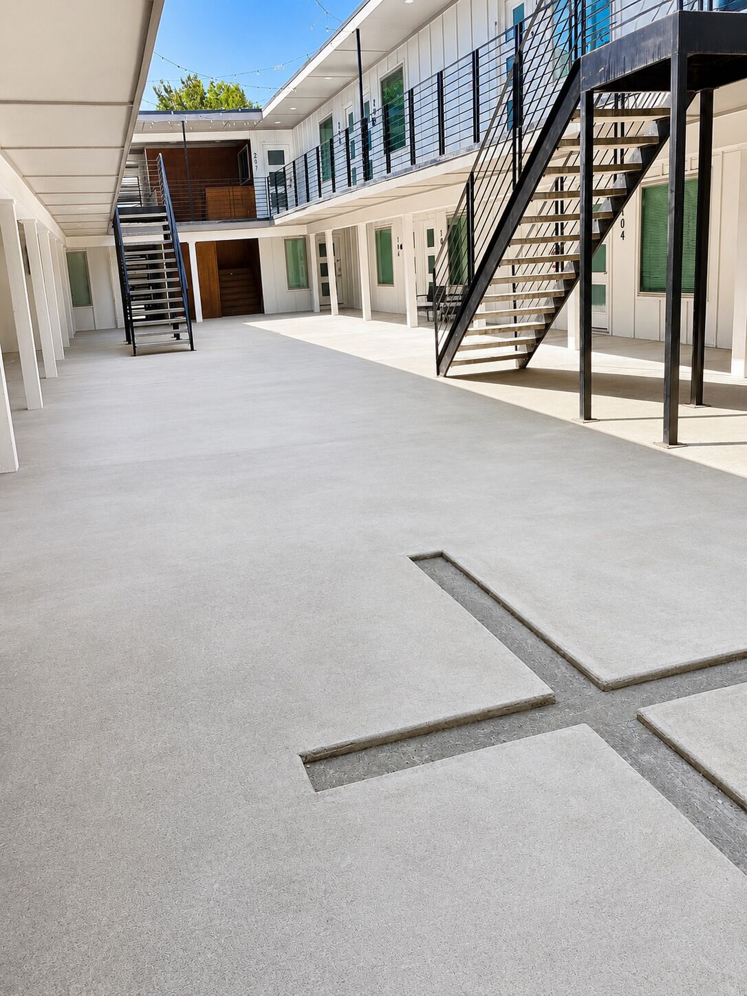 A spacious indoor area with a concrete floor, a staircase, and a series of doors leading to different rooms.