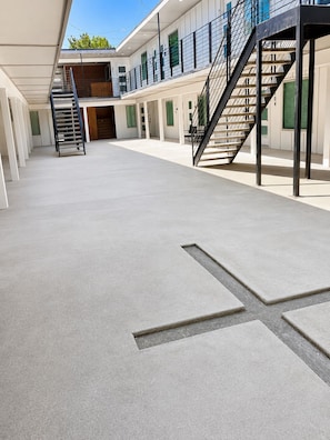 A spacious indoor area with a concrete floor, a staircase, and a series of doors leading to different rooms. - Cozy 1BR - Sleeps 4 - Walk to Downtown & Free Parking (Dallas)