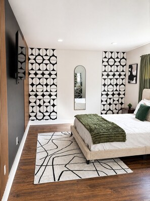 A modern bedroom with a large bed, a mirror, and a geometric-patterned wall divider. - Cozy 1BR - Sleeps 4 - Walk to Downtown & Free Parking (Dallas)