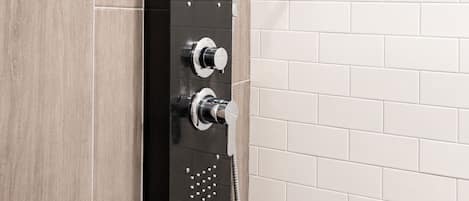 A modern shower enclosure with a handheld showerhead and control knobs.