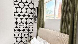 Una camera da letto con un letto, una parete decorata e una finestra con tende.