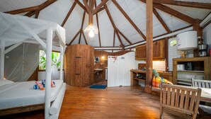Ein rustikales Blockhaus-Interieur mit Holzbalkendecke, einem Bett mit Baldachin, einer Küchenzeile und einem Essbereich.