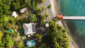 Eine Luftaufnahme eines Resorts mit Strand, Palmen und einer Anlegestelle.