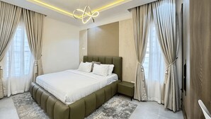 A modern bedroom with a large bed, a headboard, and a ceiling light fixture. - Premium 1-Bedroom in Victoria Island with Pool, Fast Wi-Fi & 24/7 Power (Lagos)