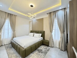 A modern bedroom with a large bed, a headboard, and a ceiling light fixture. - Premium 1-Bedroom in Victoria Island with Pool, Fast Wi-Fi & 24/7 Power (Lagos)