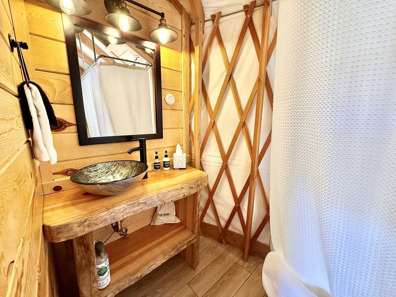 Ein Badezimmer mit Holzeinrichtung, einem großen Spiegel, einem Waschschalenbecken und einer Duschvorhang.