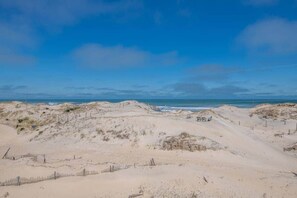 Una playa arenosa con dunas y cielo despejado.
