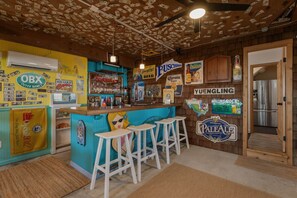 A bar area with stools, a counter, and various beer and liquor signs. - Salty Moon Outer Banks (Currituck County)