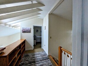 A hallway with a wooden bench, a patterned rug, and a door leading to a bedroom. - Idyllic Waterfront Cottage with Fire Pit Near Acadia National Park | Gouldsboro, Maine (Gouldsboro)