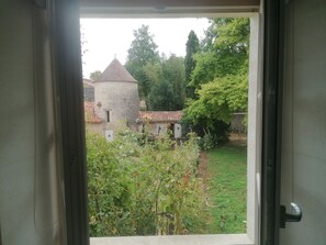 A view through an open door of a courtyard with a stone building, greenery, and a clear sky. - Air Conditionned house:  quiet, Greenery & kindness with large pool and garden (Châteauneuf-sur-Charente)