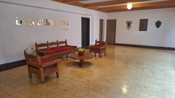 Una habitación con piso de madera, un conjunto de sofá, una mesita de centro y una pared con un letrero que dice 'DON BERNARDO Salón'.
