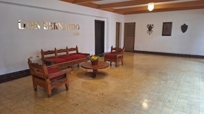 Una habitación con piso de madera, un conjunto de sofá, una mesita de centro y una pared con un letrero que dice 'DON BERNARDO Salón'.