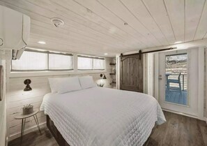 Quarto com cama grande, janela com cortinas, porta e vista para o exterior.