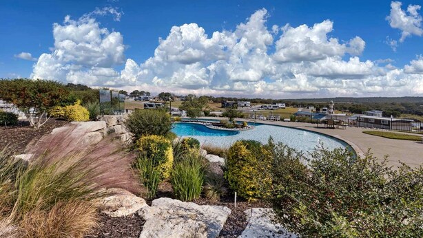 Una piscina dalla forma sinuosa, circondata da aree verdi con rocce e arbusti.