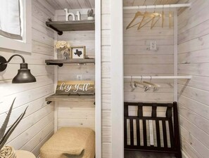 A room with a crib, shelves with decorative items, a wall-mounted lamp, and a 'hey yall' sign.