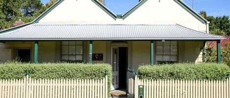 A two-story building with a gabled roof, a front door, and a picket fence.