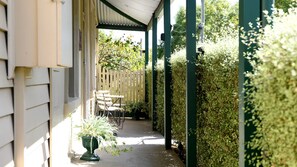 A covered outdoor area with a wooden fence, a bench, and a potted plant.