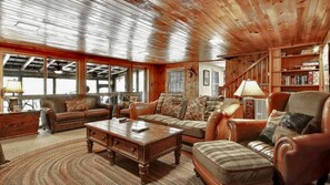 A spacious living room with leather sofas, a wooden coffee table, and a bookshelf. - Exclusive Retreat: Unique Cabin Getaway Along Norton Creek in Gatlinburg, TN (Gatlinburg)